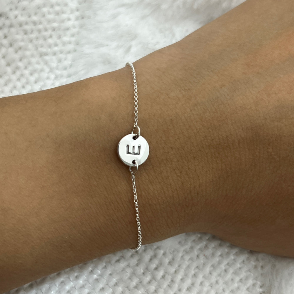 en la mano una pulsera de plata con la letra E